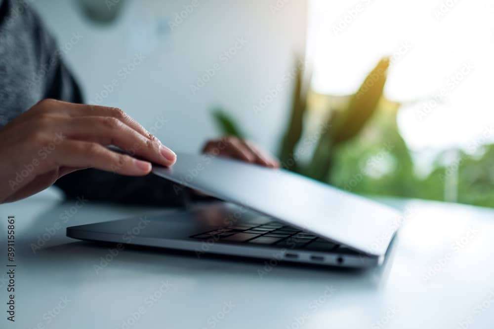 Closeup image of hands close and open a laptop computer on table after finished using it