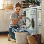 Happy housewife woman in laundry room with washing machine  .