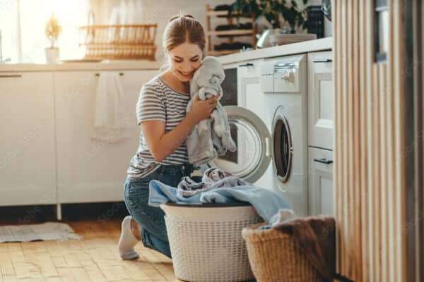 Happy housewife woman in laundry room with washing machine  .