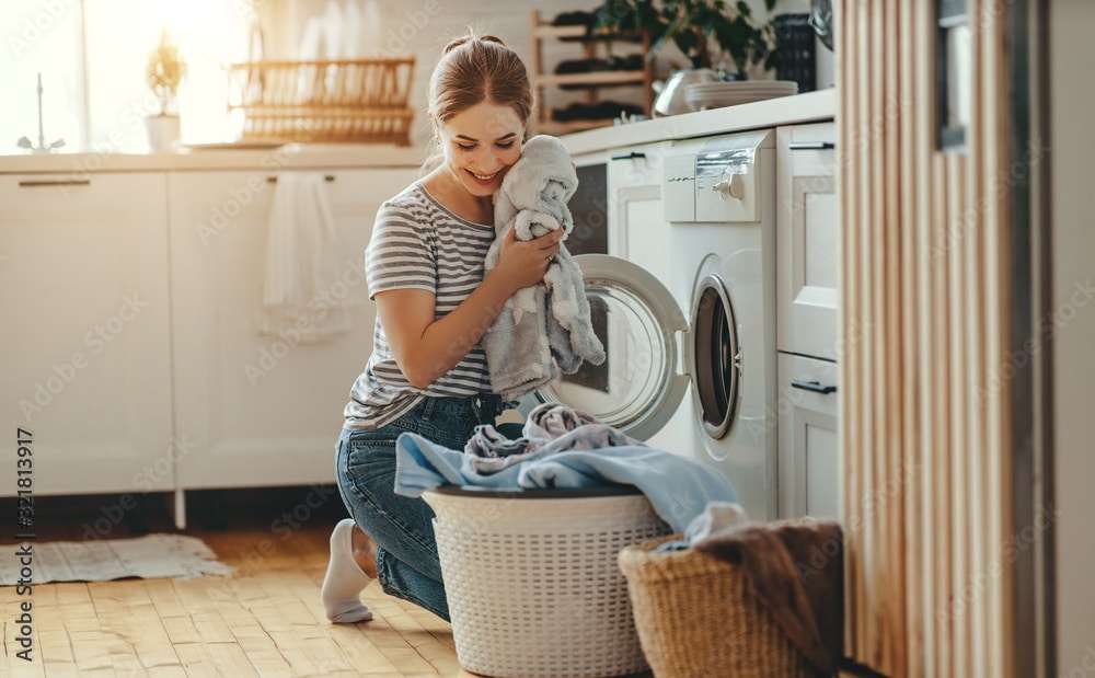 Happy housewife woman in laundry room with washing machine  .