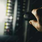 photo during a power outage with silhouette of hand holding a flashlight aimed at a fuse box