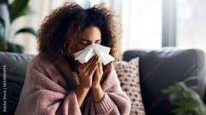 Sick woman blowing her nose on a cold winter day